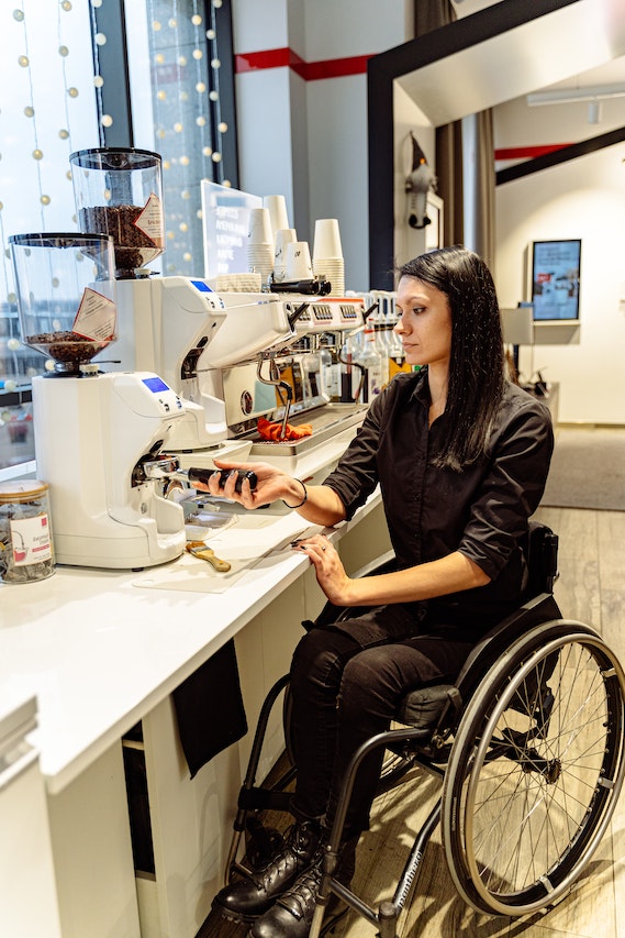 Reformas y adaptaciones para personas con discapacidad o movilidad reducida 5 Cocina adaptada para personas con movilidad reducida, mujer en silla de ruedas preparando café