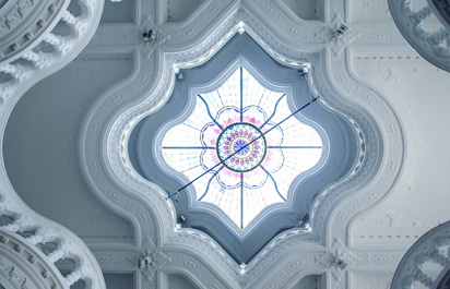 Servicios 13 Imagen de un techo de escayola decorado con hermosos dibujos en relieve, destacando una cúpula en el centro que permite la entrada de luz natural.