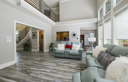 Servicios 12 Imagen de un espacioso salón recién reformado, con un estilo moderno y elegante, destacando una tarima de madera oscura en el suelo, amplios ventanales y puertas que permiten la entrada de luz natural.