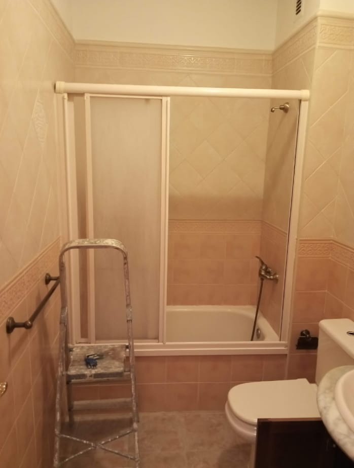 Renovación del cuarto de baño gris 3 Cuarto de baño antiguo con azulejos marrones y diseño tradicional.