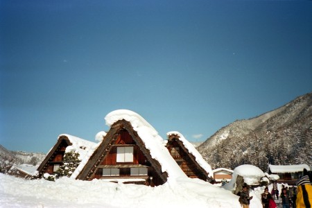 Un grupo de turistas de pie en la nieve, con montañas nevadas y árboles en el fondo. Los turistas están vestidos con ropa de invierno y llevan mochilas. El cielo está despejado y el sol está brillando. Un grupo de turistas de pie en la nieve, con montañas nevadas y árboles en el fondo.