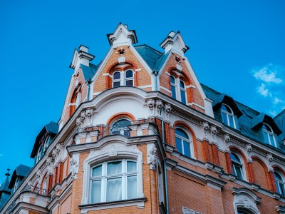 Esta foto muestra una calle urbana con edificios de apartamentos y un cielo azul. Los edificios son de diferentes alturas y colores, y están llenos de ventanas. La calle está vacía, y se puede ver que hay mucho sol. La foto es un recordatorio de la belleza y la diversidad de la arquitectura urbana. Una foto de una calle urbana con edificios de apartamentos y un cielo azul.