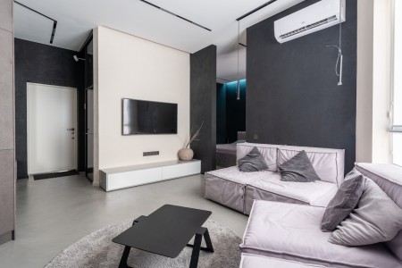 Este salón de tonos crema y detalles en gris oscuro ofrece una climatización óptima para disfrutar de un ambiente acogedor y relajante. Confort y estilo en un salón bien climatizado