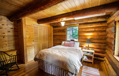 Servicios 8  Imagen de un dormitorio recién reformado, con un encantador estilo rústico, donde predominan los elementos de madera. Las paredes, el techo, el armario y la cama están elaborados con madera, creando un ambiente cálido y acogedor.