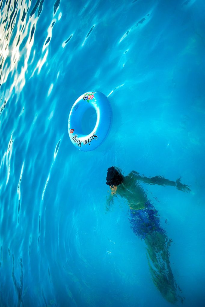 Renovación de una piscina 3 Imagen de un niño disfrutando de un baño en una piscina, con un flotador en la superficie mientras el niño se sumerge en el agua.