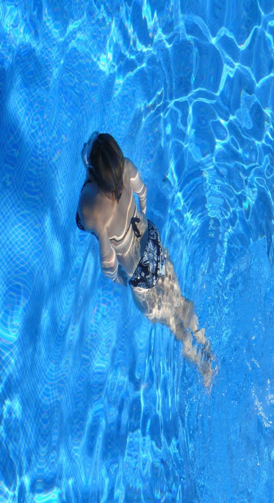 Renovación de una piscina 7 Imagen de una mujer nadando grácilmente en una piscina recién reformada, disfrutando de un momento de serenidad y libertad en el agua.