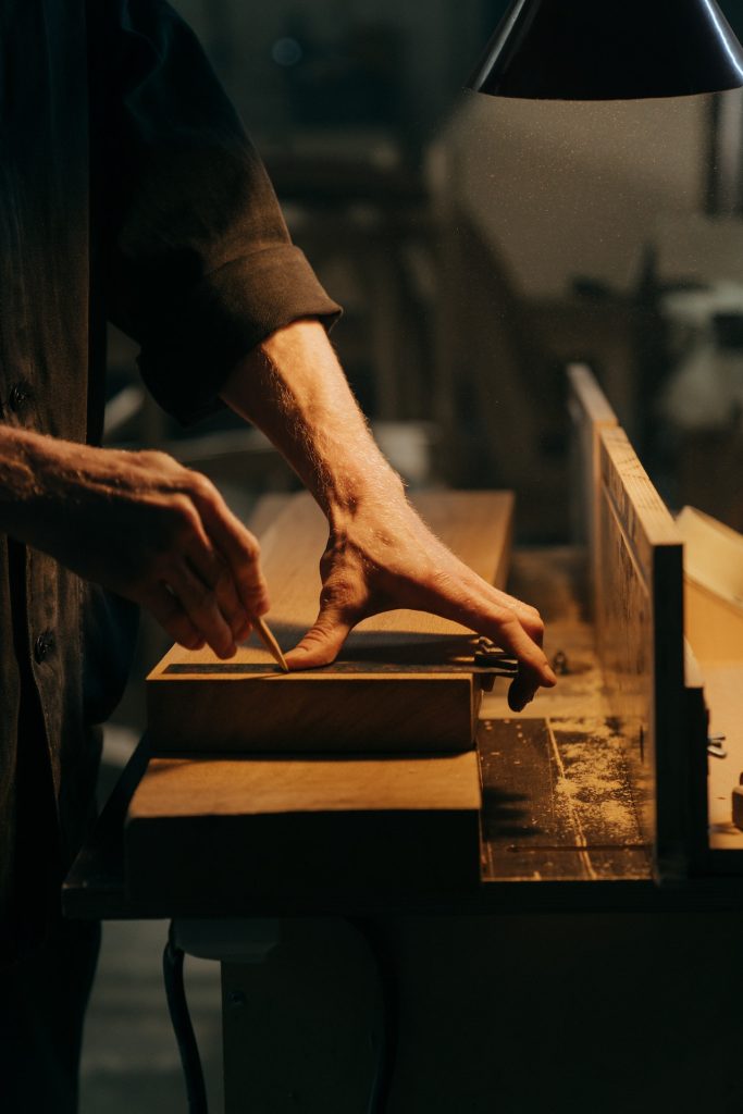 Carpintería de madera, aluminio y PVC 1 Trabajador meticuloso midiendo y trazando una madera en su banco de trabajo