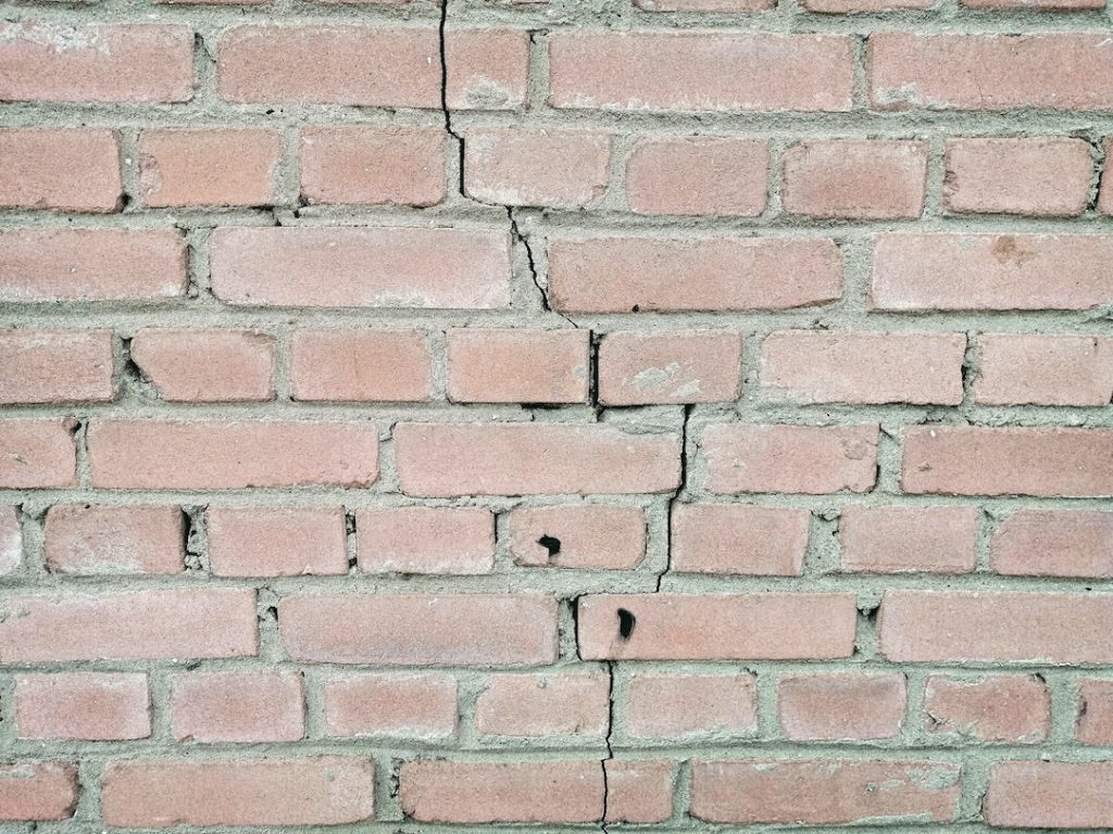 Reparación de daños estructurales en paredes, como grietas profundas o desplazamientos 2 Pared de ladrillos deteriorada con raja y desplazamiento