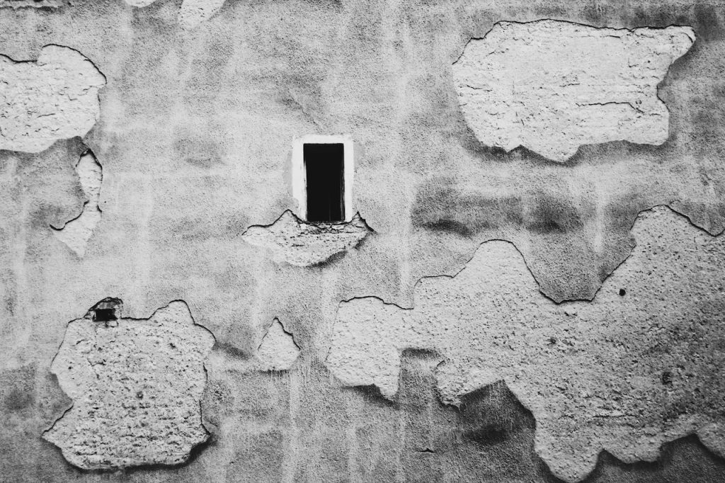 Reconstrucción de secciones dañadas de paredes de ladrillo o cemento 2 Pared desgastada y agrietada con desconchones y tonos grisáceos del paso del tiempo