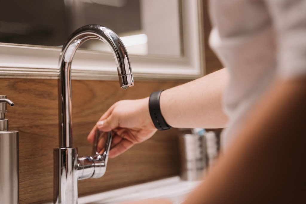 Saneamiento y desinfección de sistemas de agua 2 Grifo de cocina recién instalado con la mano de una mujer abriendo el agua